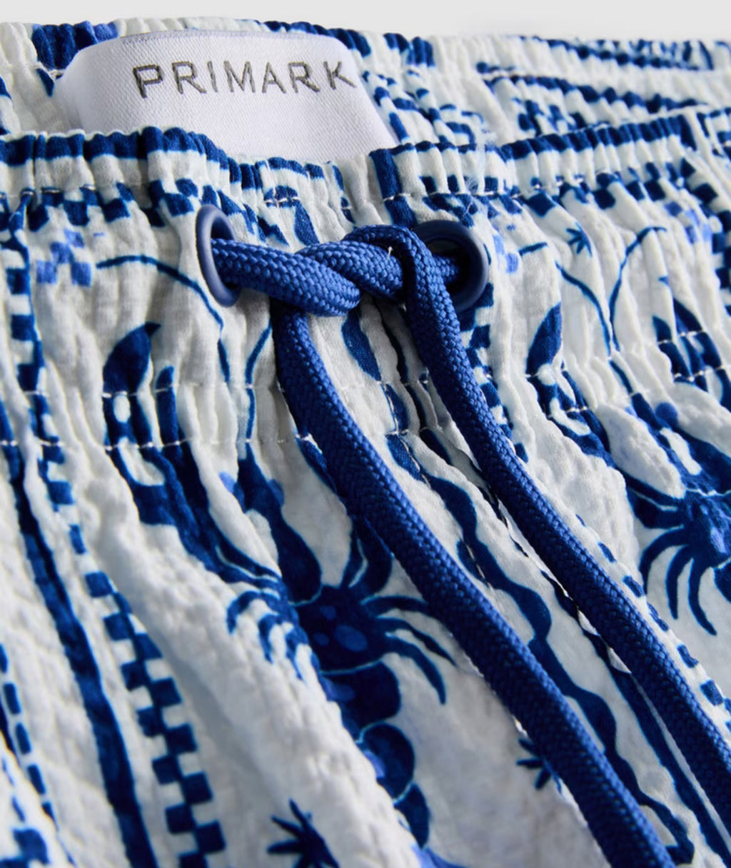 A pair of swimming shorts with a textured finish, drawstring, and mesh lining