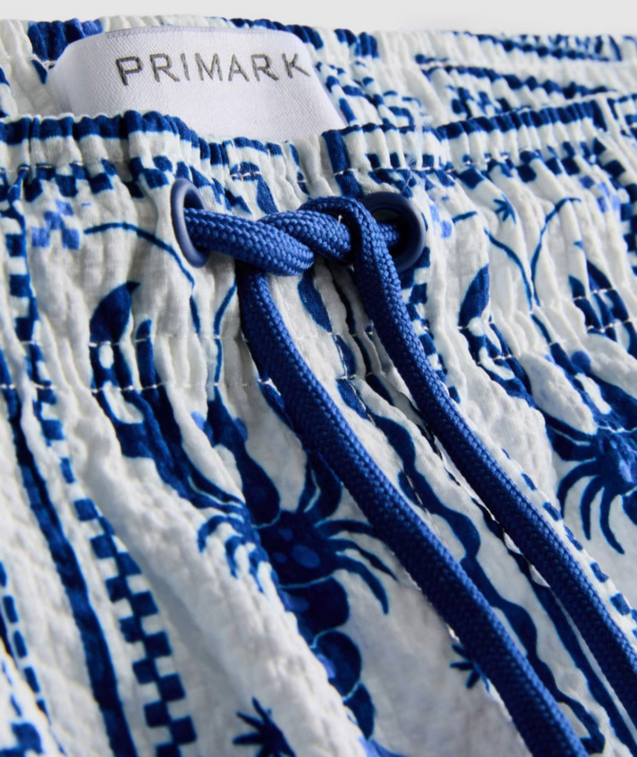 A pair of swimming shorts with a textured finish, drawstring, and mesh lining