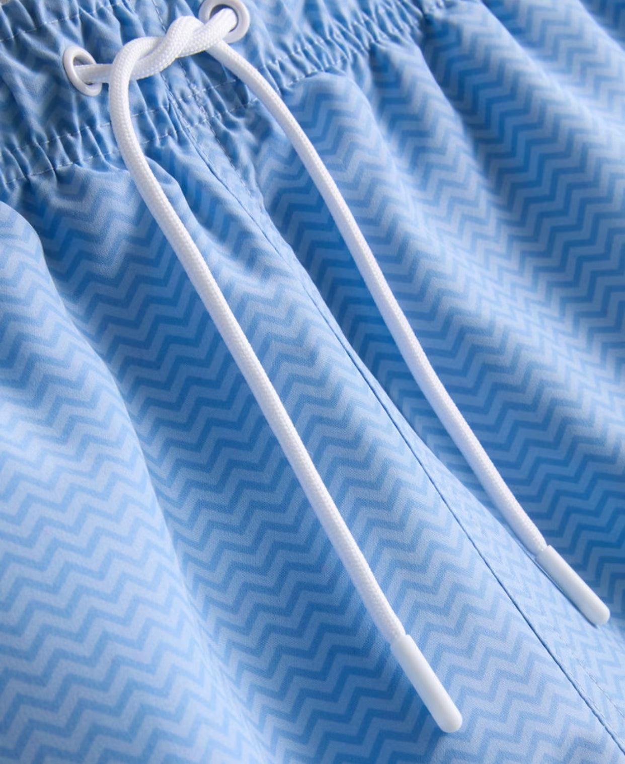 A pair of drawstring swimming shorts with a mesh lining and a zig-zag pattern
