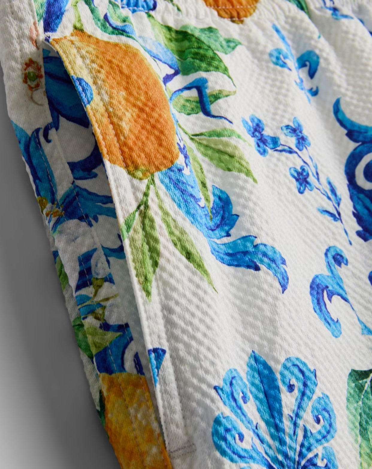 A pair of textured swimming shorts with orange and ocean design with a drawstring waistline