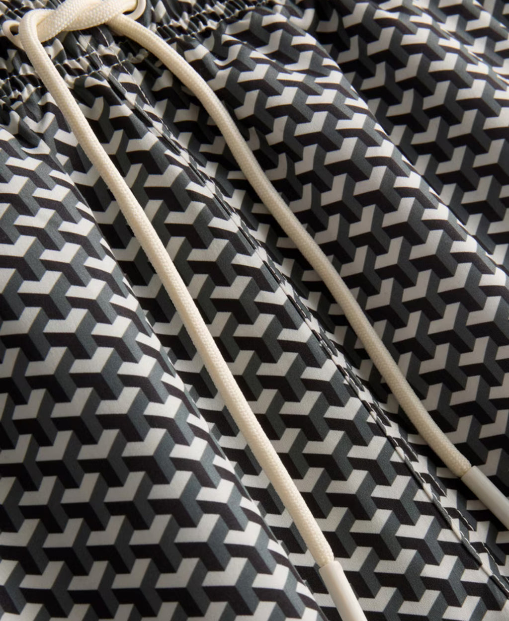 A pair of swimming shorts with a geometric design, mesh lining, and a drawstring waistline