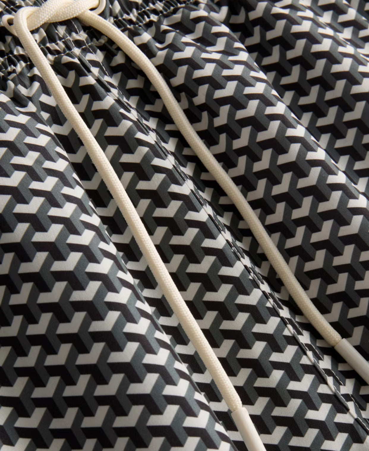 A pair of swimming shorts with a geometric design, mesh lining, and a drawstring waistline